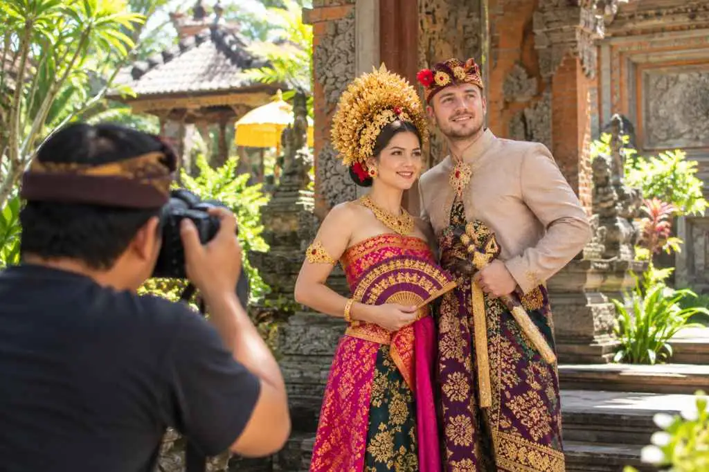 Photographer capturing a couple in traditional Balinese costumes during a Balinese Costume Photoshoot at a temple-style setting