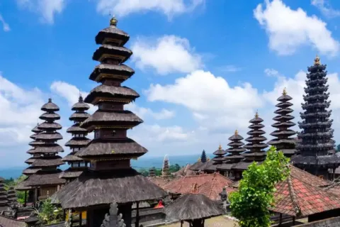 Multi-tiered meru shrines at Besakih Temple against a bright blue sky during the Besakih Temple Tour.