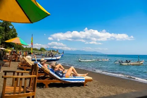 Travelers relaxing on Lovina Beach beside traditional boats