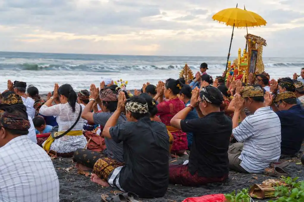 Balinese Hindu community praying during a cremation ceremony on the beach