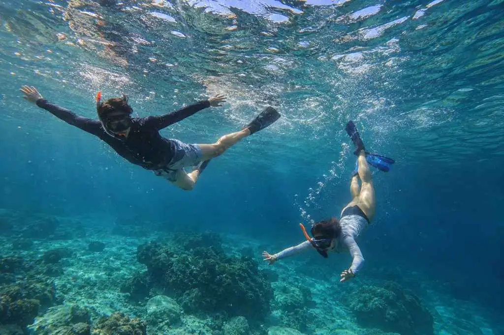 Travelers snorkeling above a colorful coral reef near Nusa Lembongan