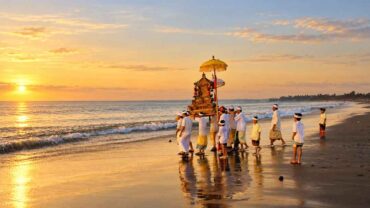 Balinese Hindu procession carrying ceremonial offerings along the coast
