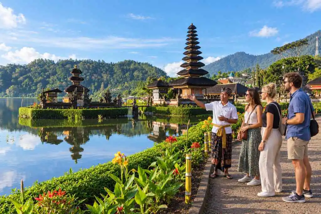 Tourists listening to a Balinese guide at Ulun Danu Beratan Temple beside Lake Beratan.