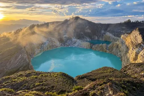 Two turquoise volcanic crater lakes surrounded by rugged mountains at Kelimutu.