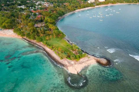 Aerial view of a tropical island with green landscapes and turquoise water in the Bali Lombok 9 Days Package