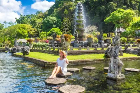 Visitor sitting on a stepping stone in the ornamental pond at Tirta Gangga Water Palace
