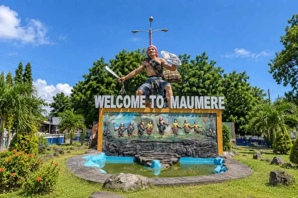 Welcome to Maumere monument featuring a traditional warrior statue and cultural mural.